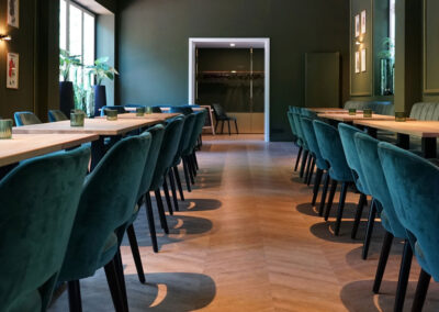 Innenraum von Lillys Parkcafe in Bückeburg mit neuen Böden, grünen Wänden, Holztischen und Blick zur Theke.