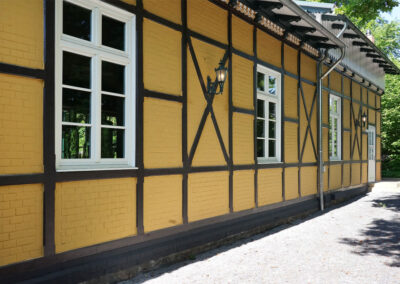 Frisch gestrichene Fassade von Lilliys Parkcafe im Schlosspark Bückeburg mit gelben Wänden und dunklem Fachwerk.