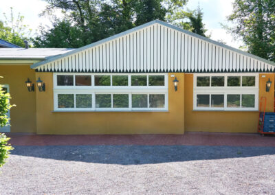 Gebäudeseite von Lillys Parkcafe in Bückeburg mit gelber Fassade, weißen Fenstern und dekorativem Giebel nach Renovierung.