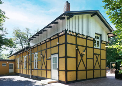 Fachwerkfassade von Lillys Park Café in Bückeburg mit gelbem Anstrich, weißen Fenstern und dekorativem Giebel.